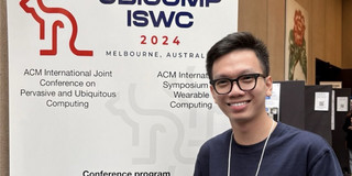 Toan in front of a UbiComp 2024 banner